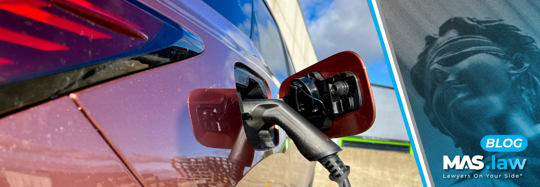 A red, electric car being charged | MAS Law