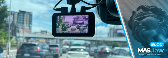 A dashcam mounted on a car windshield recording traffic under an overpass during heavy congestion.