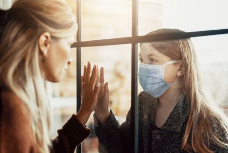 Mother and daughter separated by a glass window