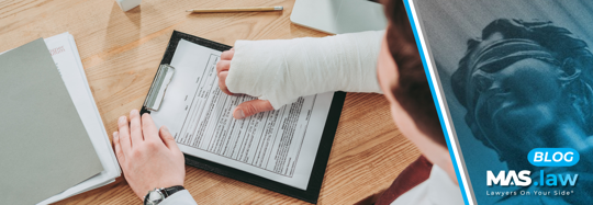 Injured person with a bandaged hand reviewing paperwork with an insurance representative | MAS Law