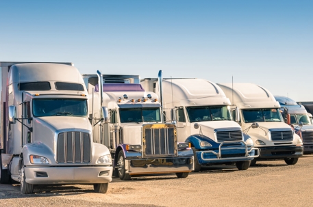 five semi trucks lined up parked next to each other