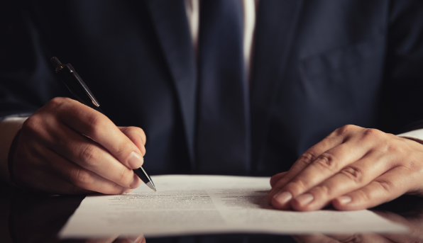 A man in a navy suit writing a demand letter | MAS Law